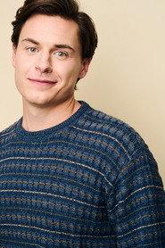 Kieran Barry as TV News Anchor in (Zero, Infinity) 2025